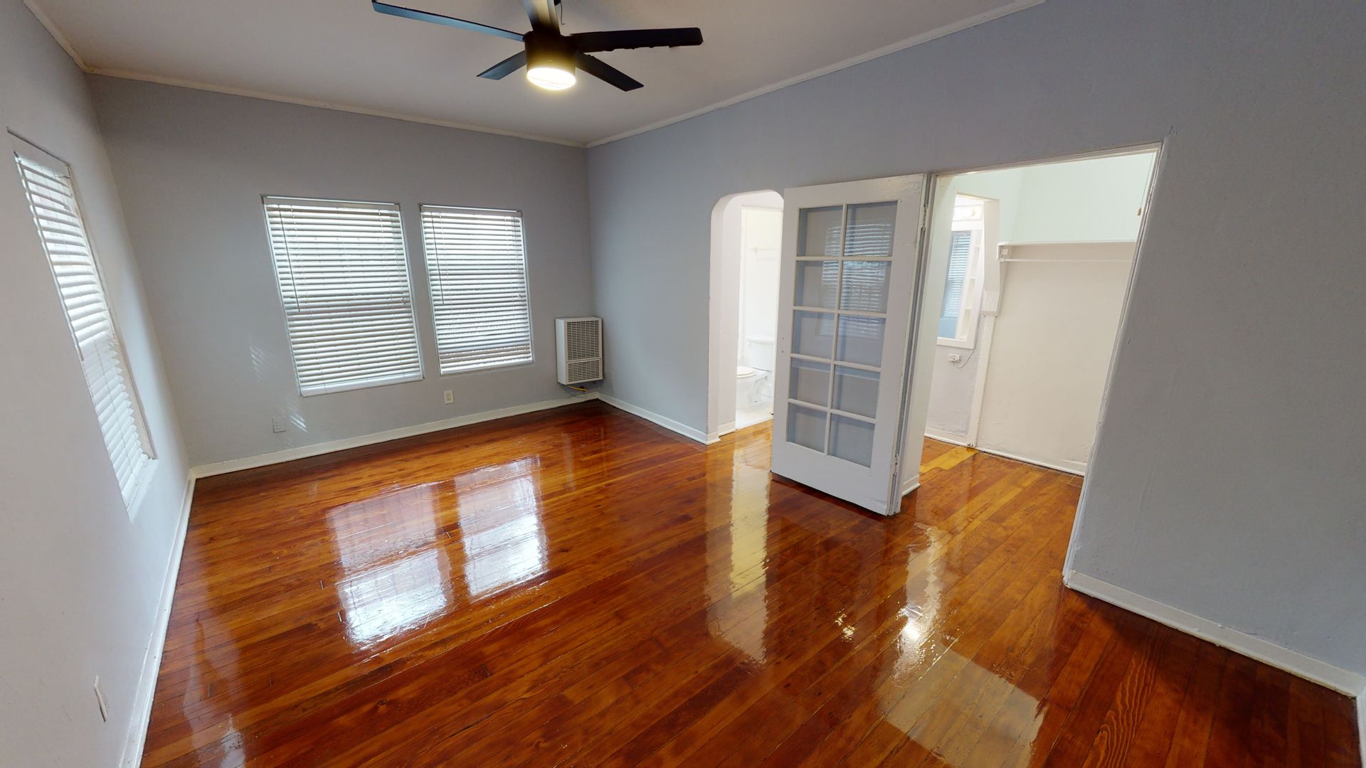 Room with hardwood floors, light blue walls, and French doors leading to another area.
