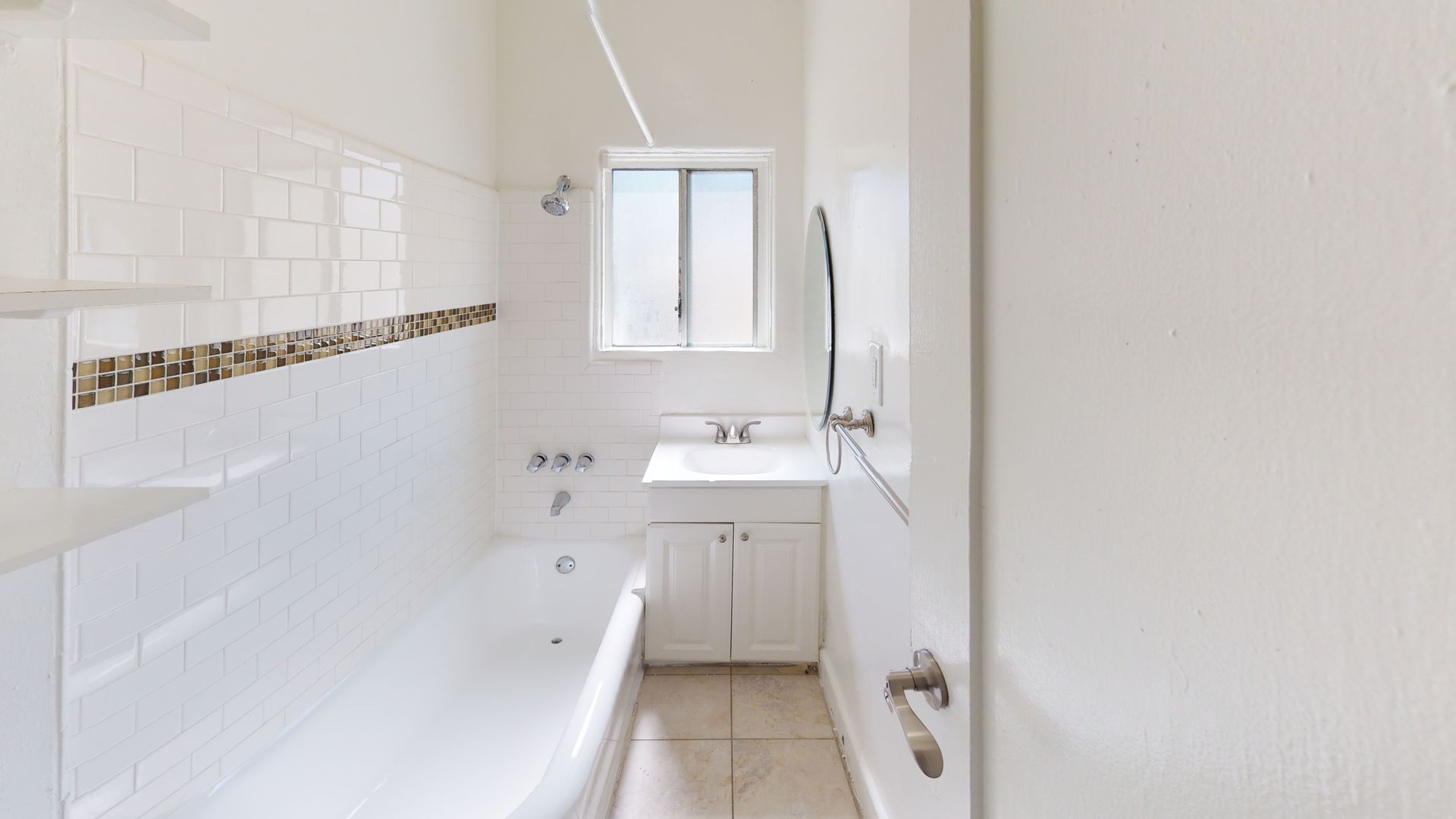 White tiled bathroom with tub, sink, and window.