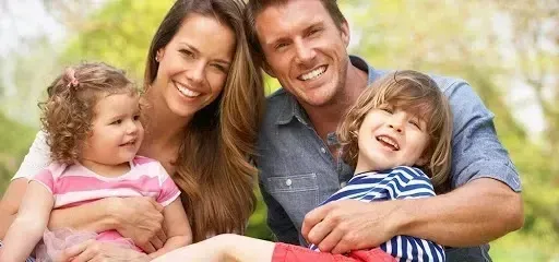 Chimney sweep portland maine-Smiling family of four, a father and mother holding their two young children outdoors.