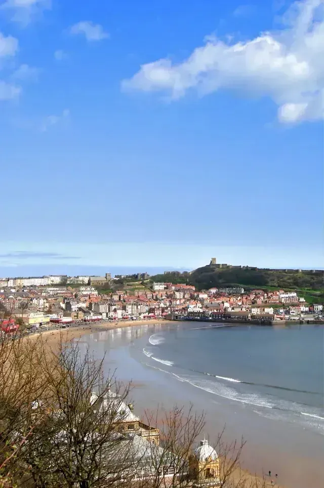 Chimney sweep portland maine -Coastal town with a crescent-shaped beach and castle on a hill under a blue sky.