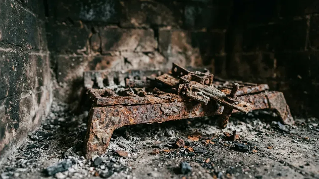 Close-up of rusted and corroded metal pieces inside a chimney firebox.