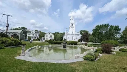 Chimney sweep portland maine-White church steeple towers over a park with a decorative fountain and surrounding houses under a cloudy sky.