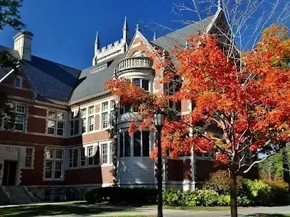 Chimney sweep portland maine - Gothic-style brick building with autumn foliage in the foreground under a clear blue sky.