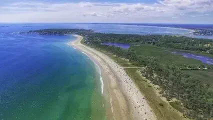 Chimney sweep portland maine - Aerial view of a crowded sandy beach curving along a bright blue ocean with green marshland and trees in the background under a cloudy sky.