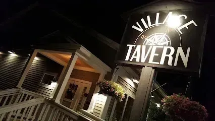Chimney sweep portland maine- The Village Tavern sign is lit up at night in front of the building's entrance.