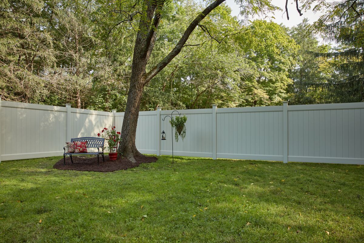 A backyard with a white fence and a tree.