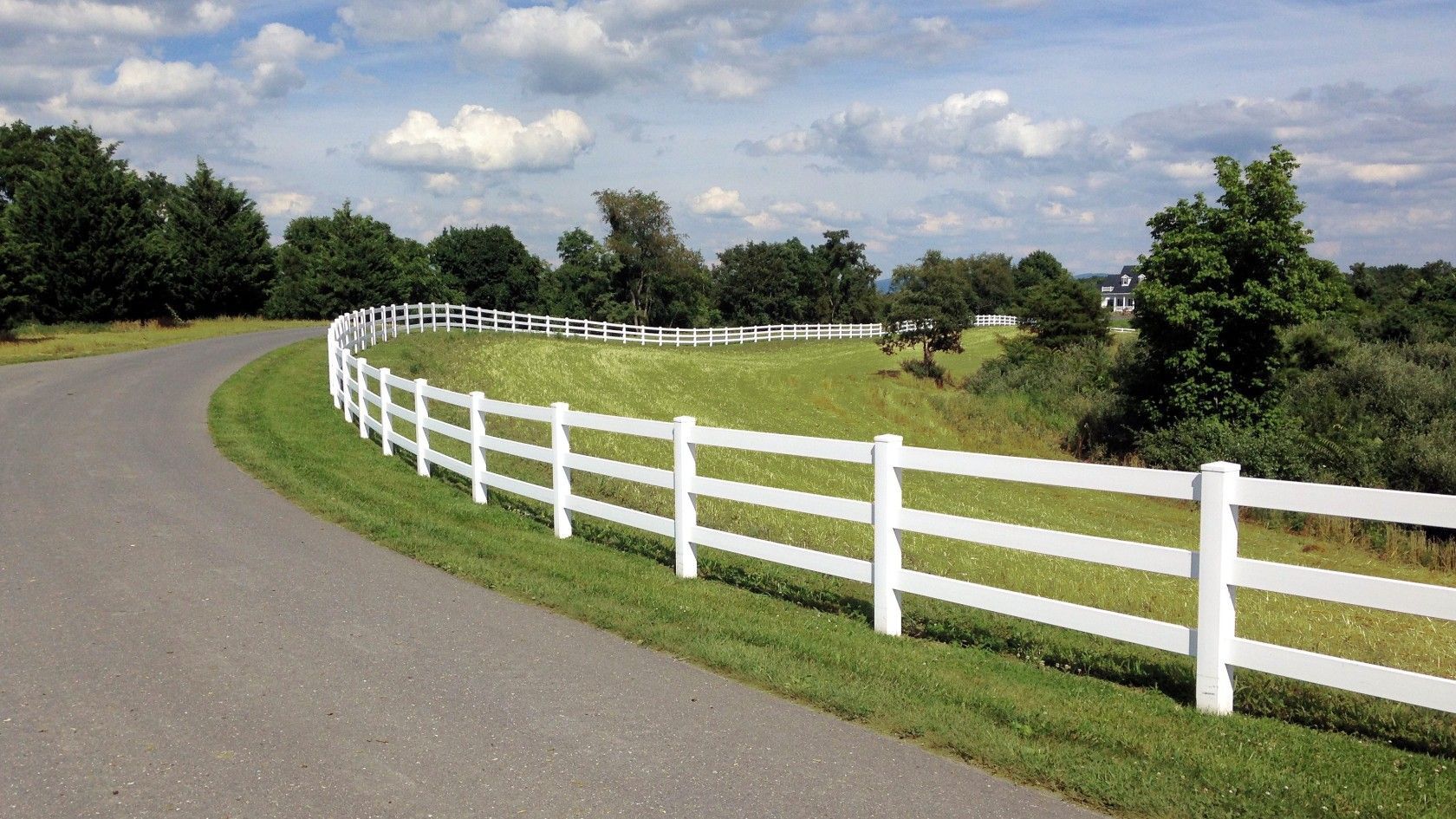 A white fence is along the side of a road.