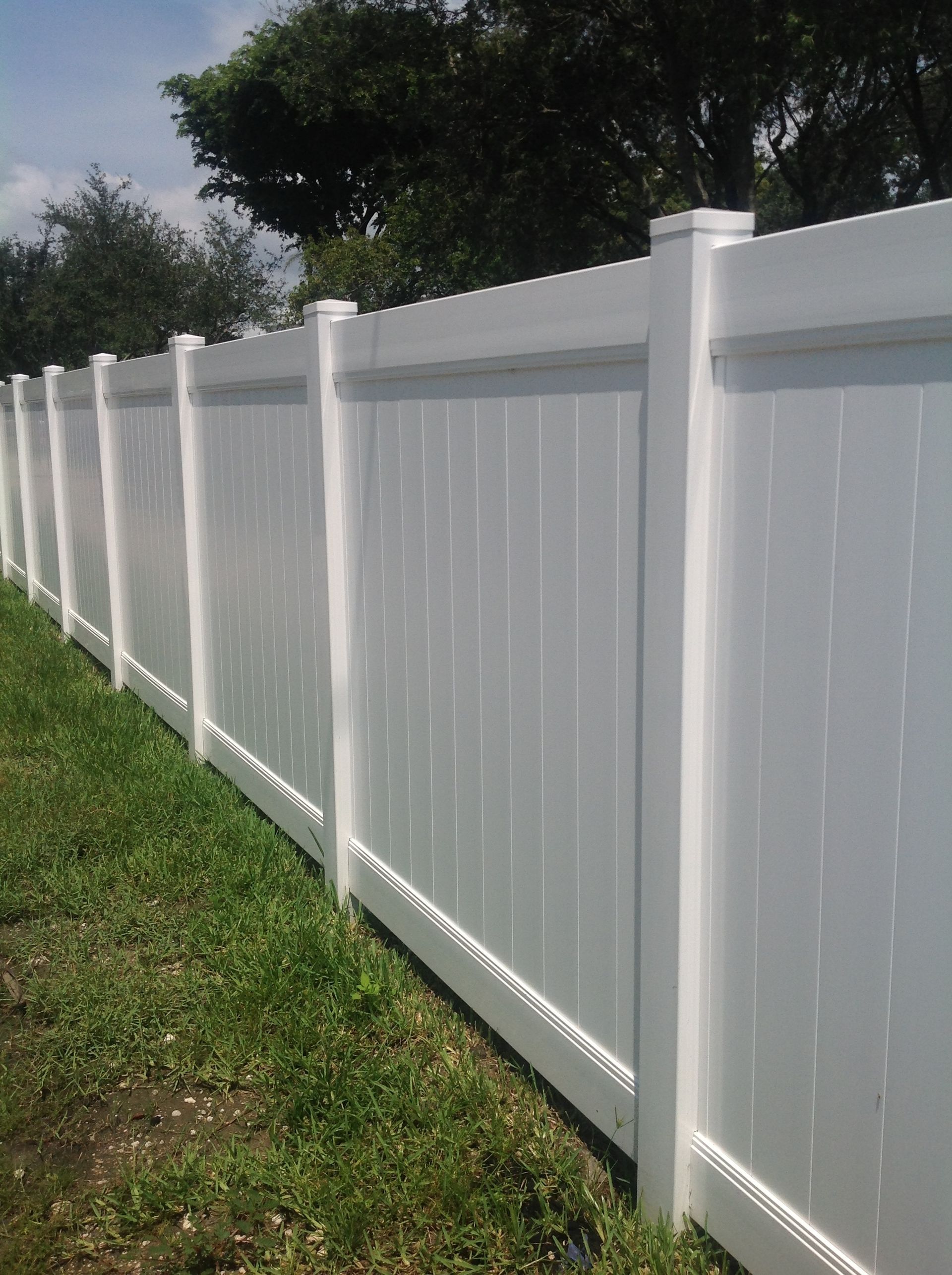 A white fence is surrounded by grass and trees.