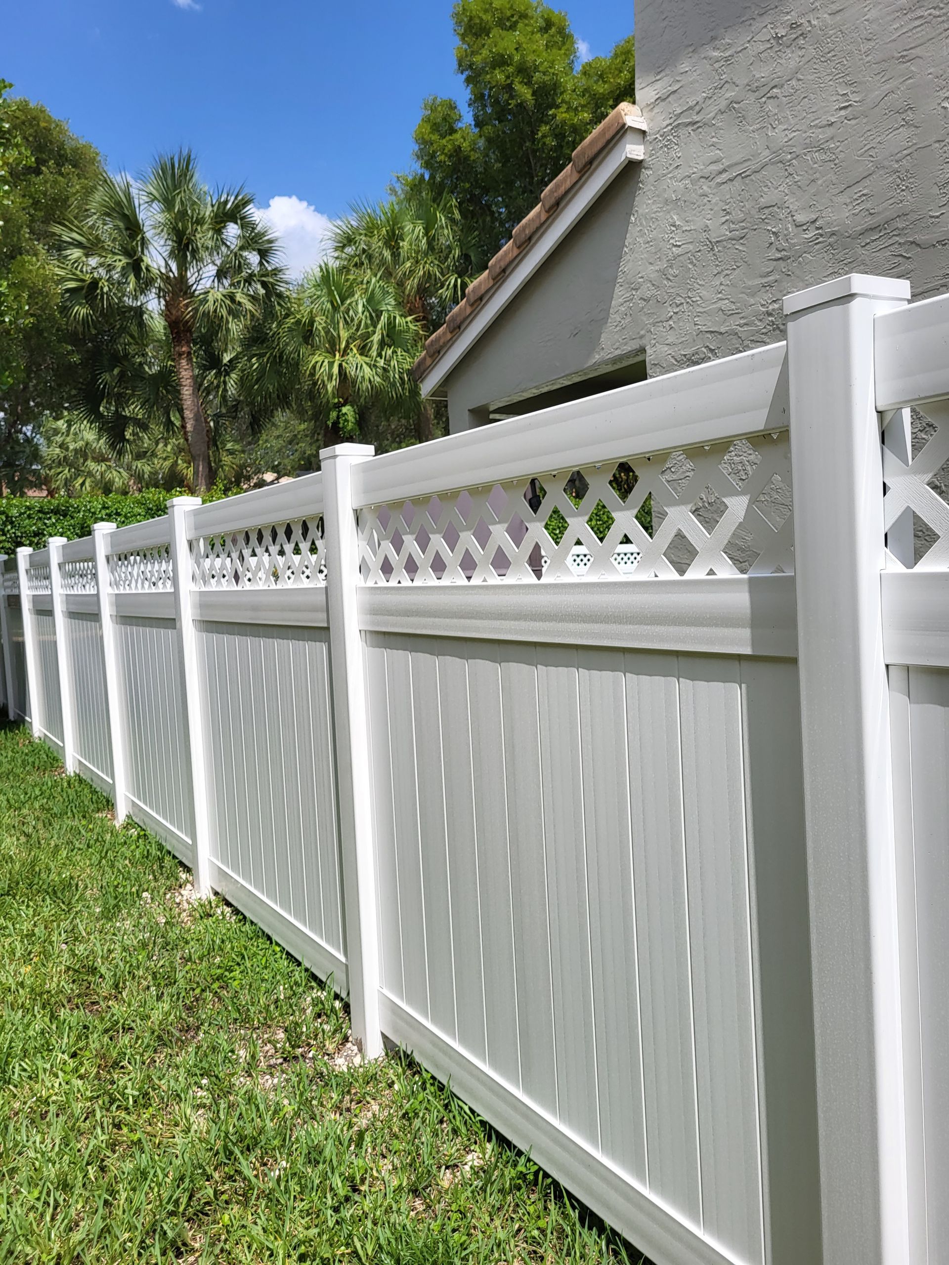 A white fence is sitting in the grass in front of a house.
