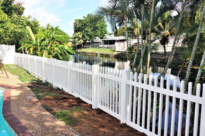 A white picket fence surrounds a swimming pool.