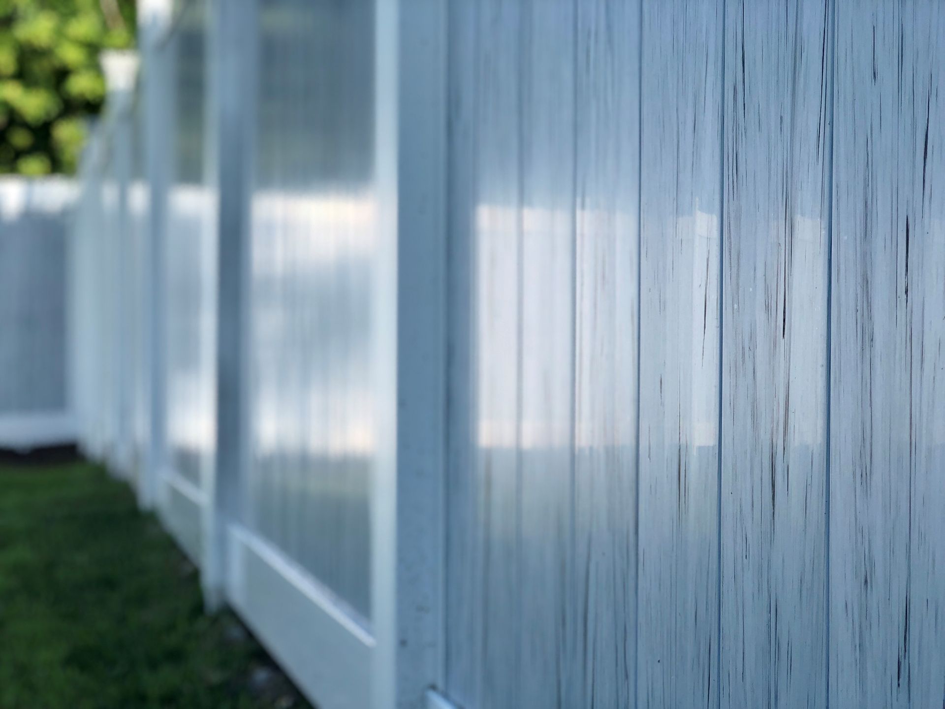 A close up of a white wooden fence in a backyard.