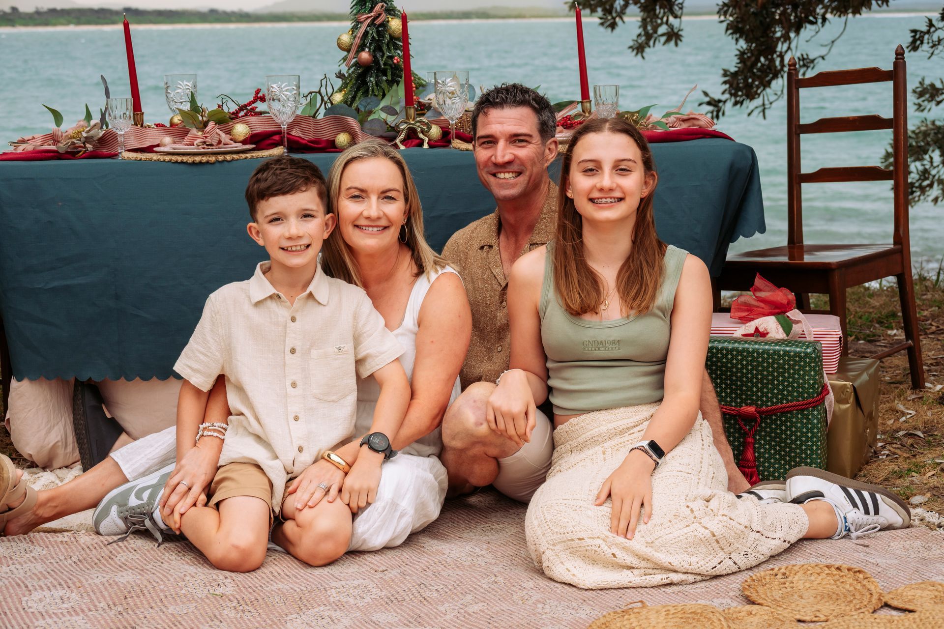 Family sitting in front of a table with Christmas decorations near a body of water. - AA Automotive Repairs in Forster