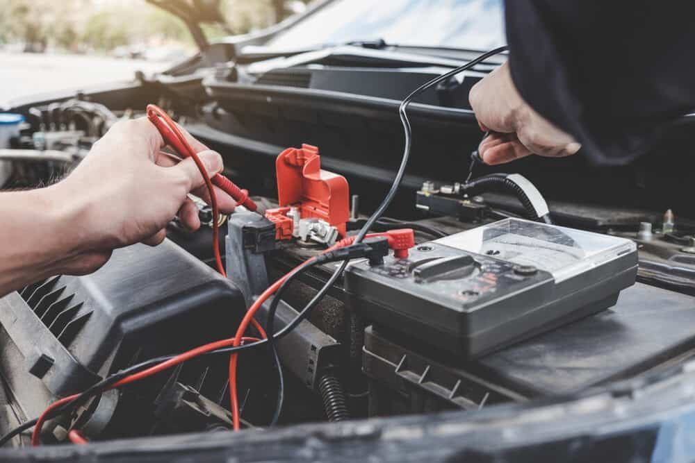 A Person is Working on a Car Battery With a Multimeter — AA Automotive Repairs in Forster, NSW