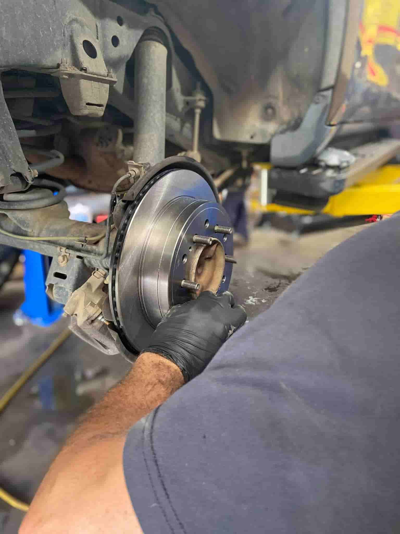 A Man is Working on a Brake Disc on a Car — AA Automotive Repairs in Forster, NSW