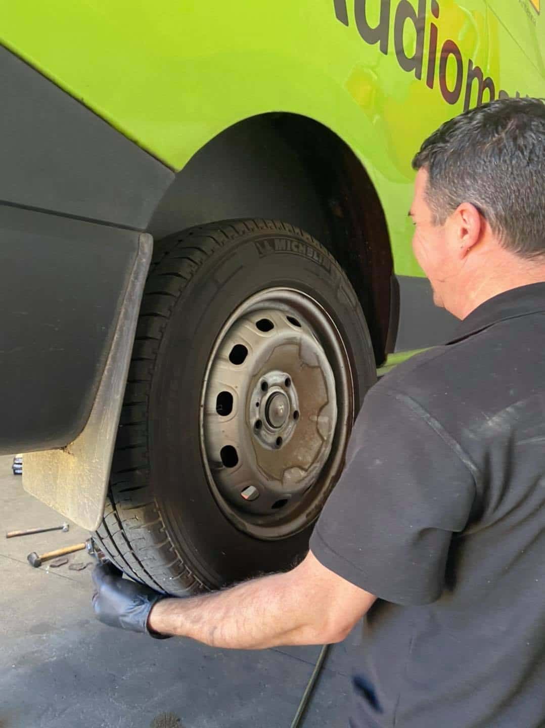 A Man is Changing a Tyre on a Green Van — AA Automotive Repairs in Forster, NSW