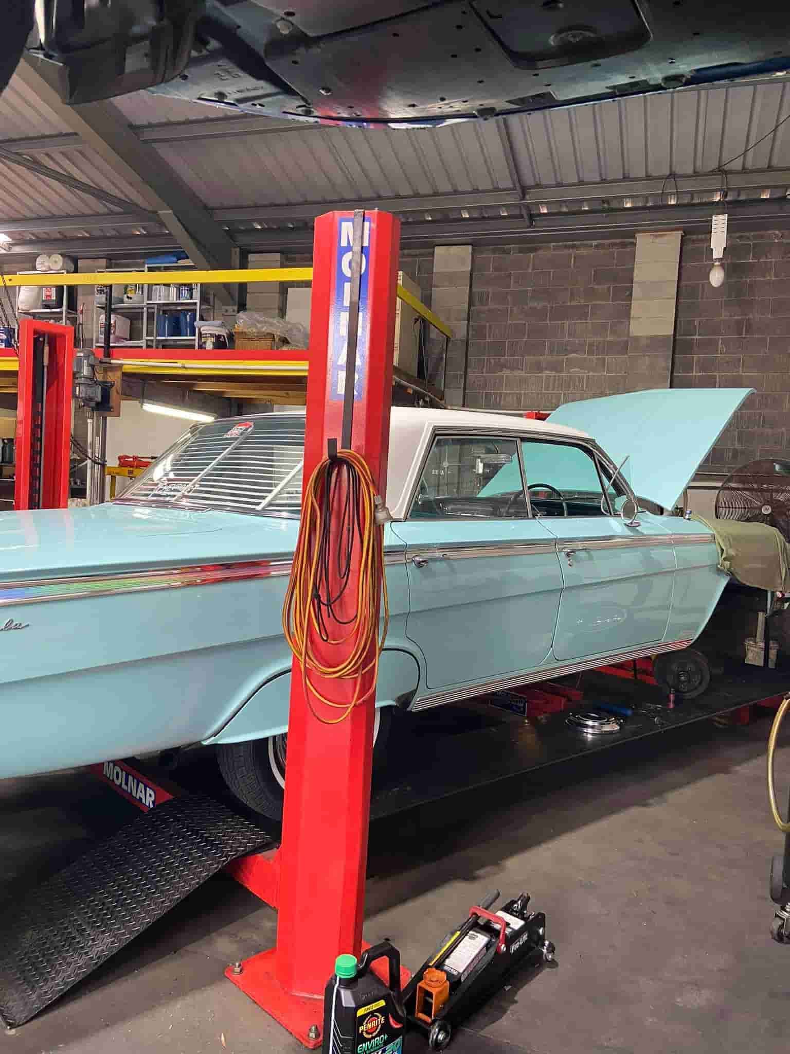 A Blue Car is Sitting on a Red Lift in a Garage — AA Automotive Repairs in Forster, NSW