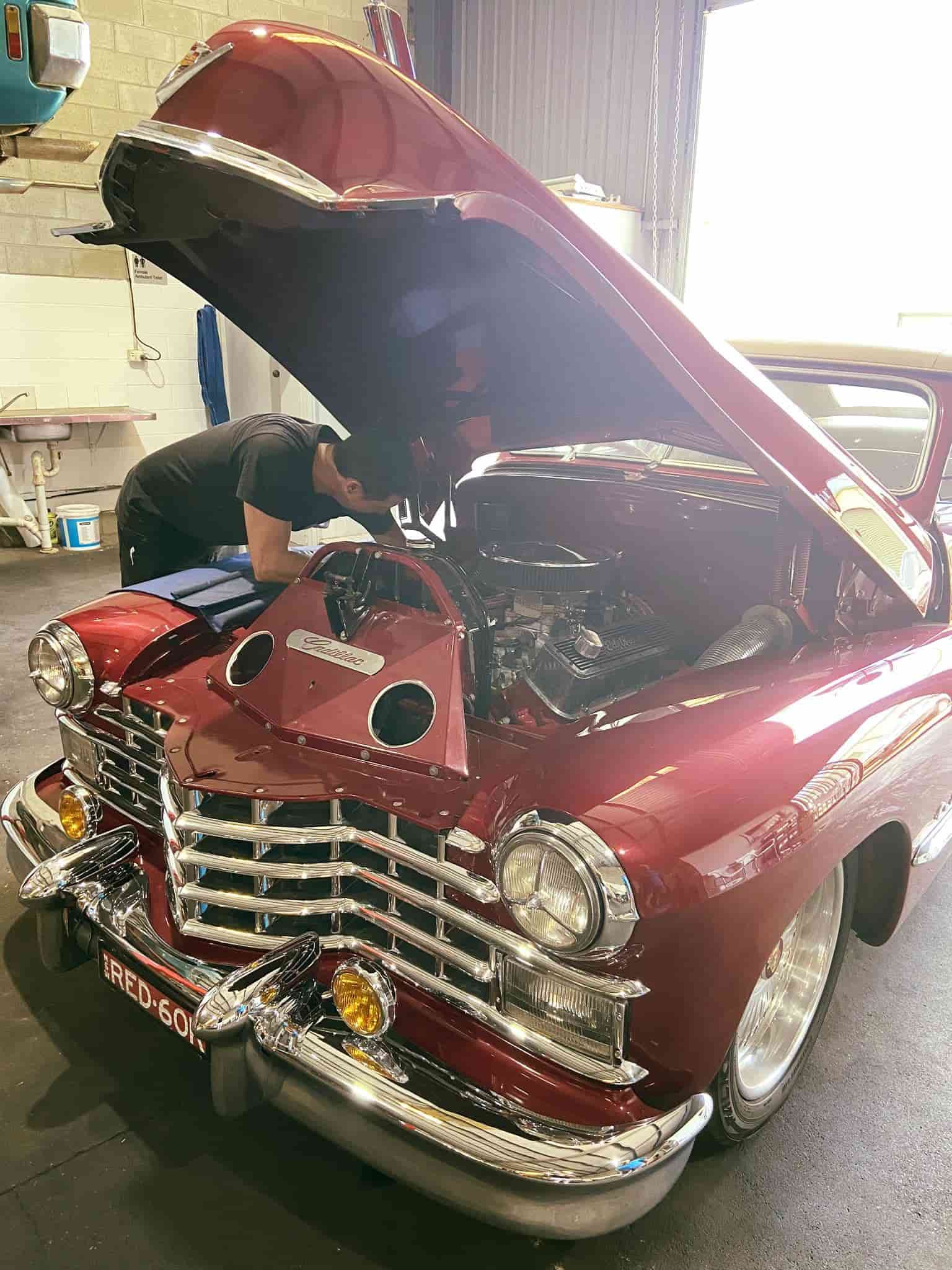 A Man is Working on a Red Car With the Hood Open in a Garage — AA Automotive Repairs in Forster, NSW