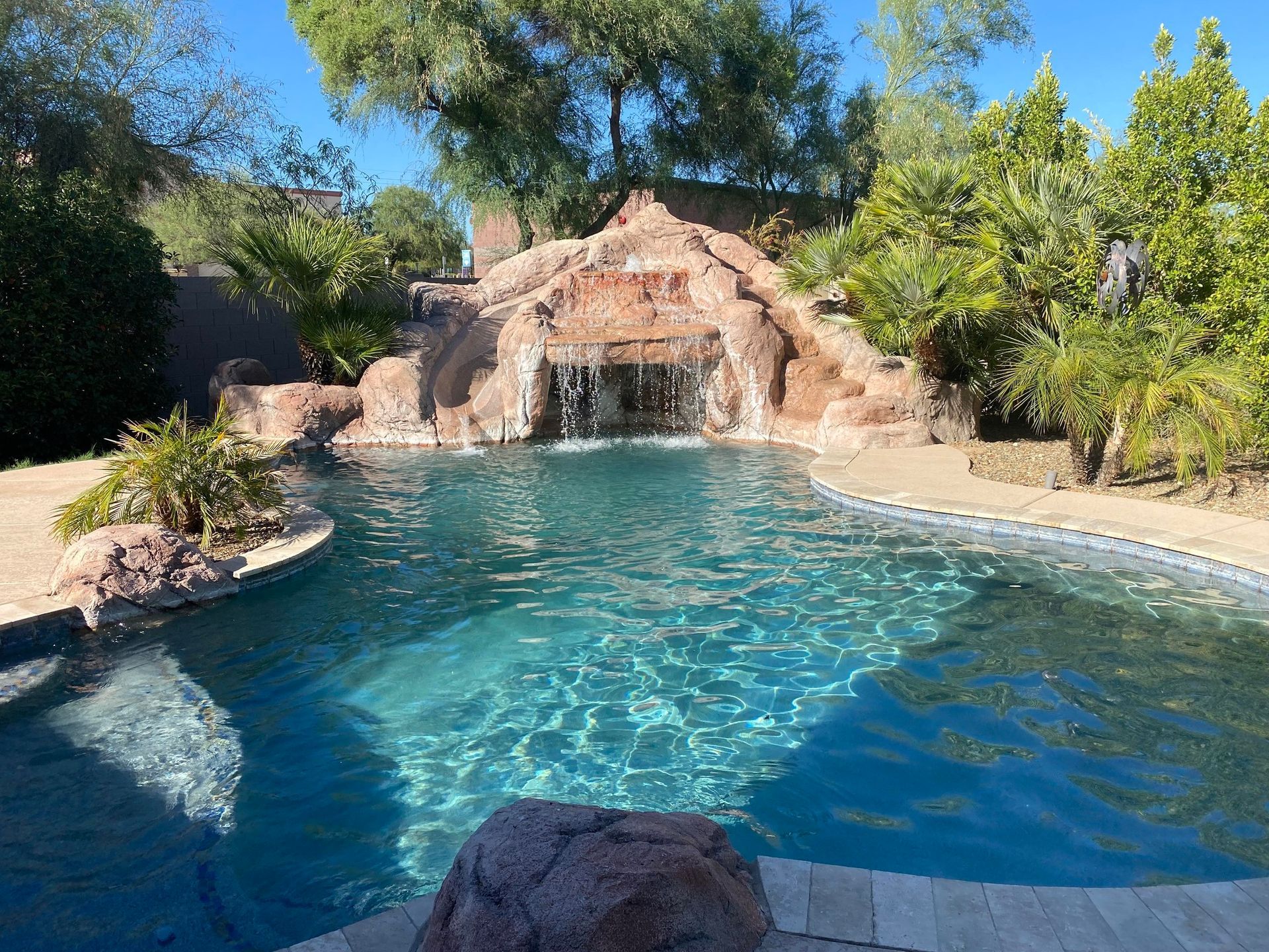 A large swimming pool with a waterfall in the background