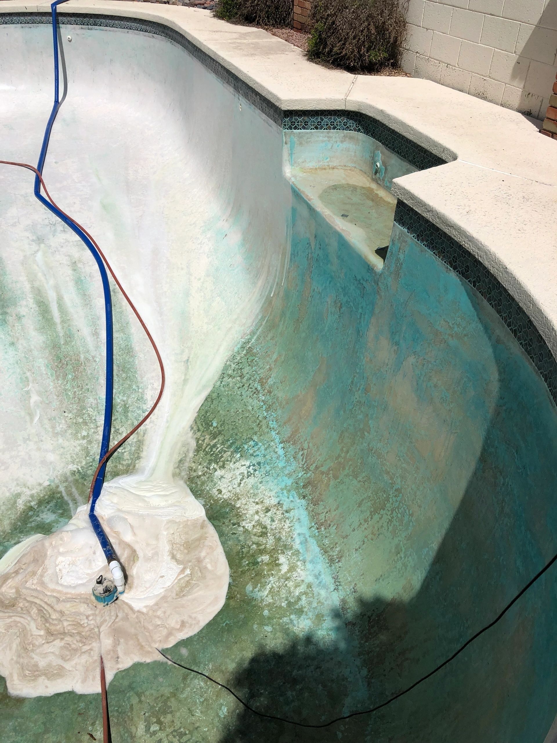 A hose is being used to clean a swimming pool.