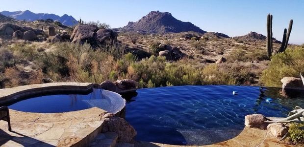 A swimming pool in the desert with mountains in the background