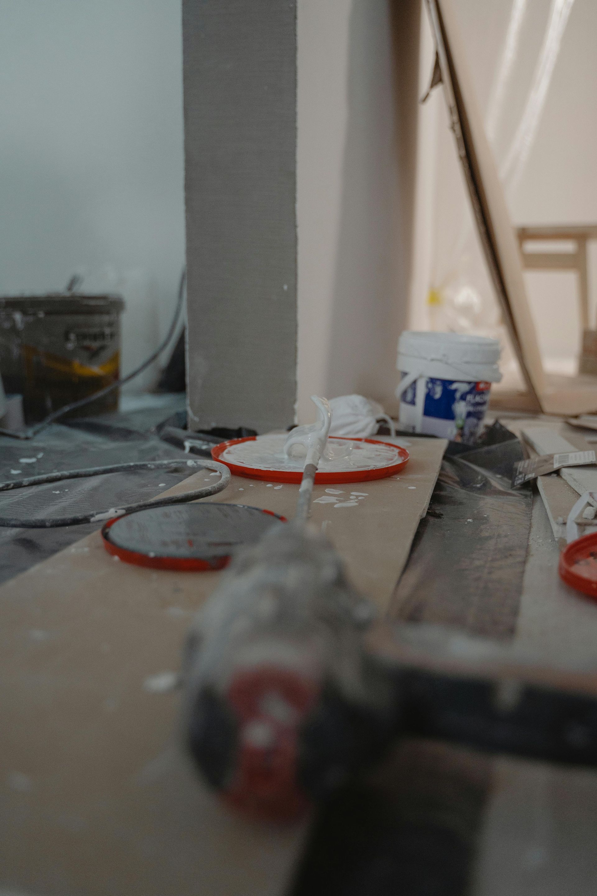 A hammer is sitting on a table next to a bucket of paint.