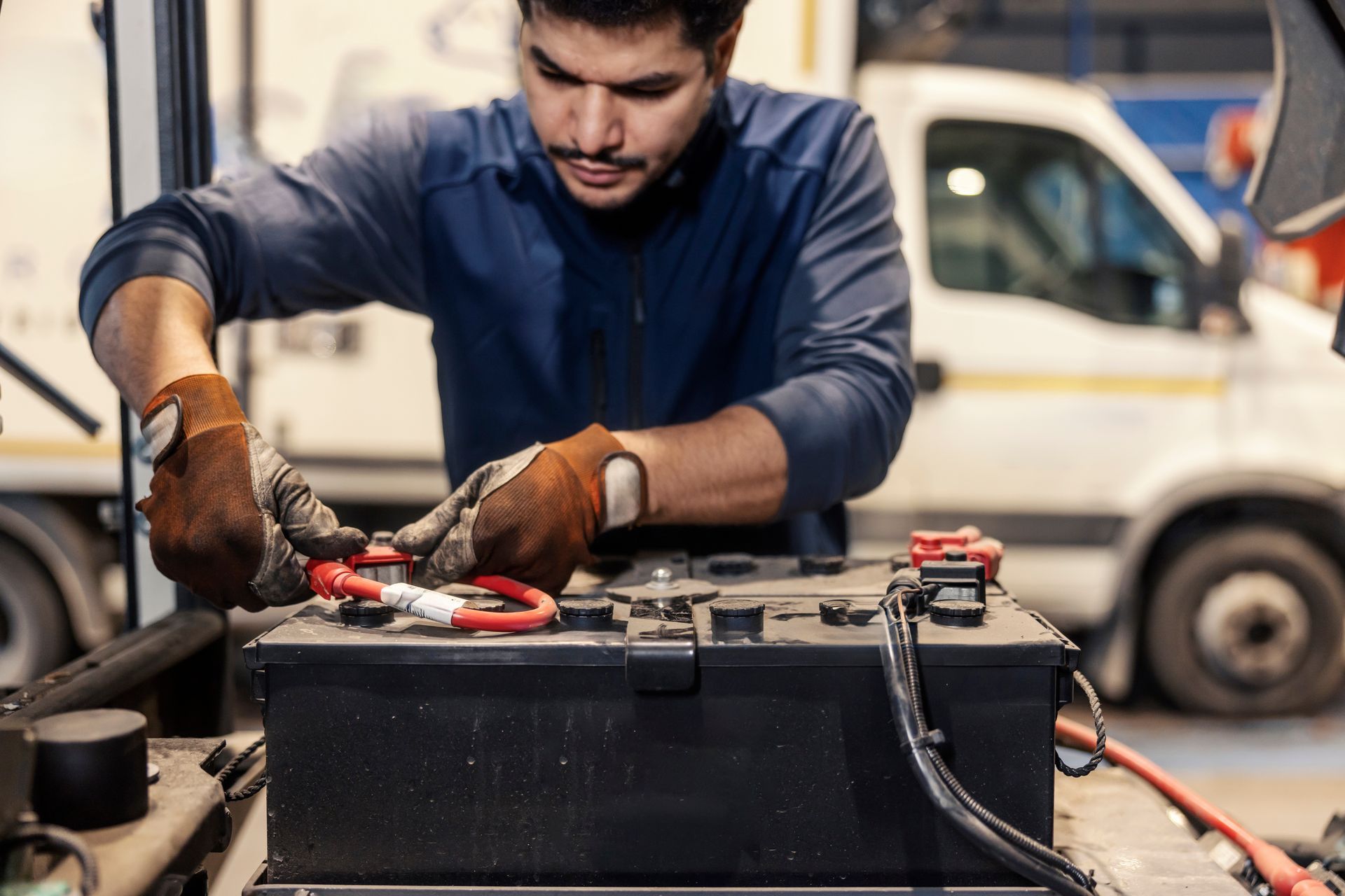 Mechanic using tools to repair a car battery in a workshop
