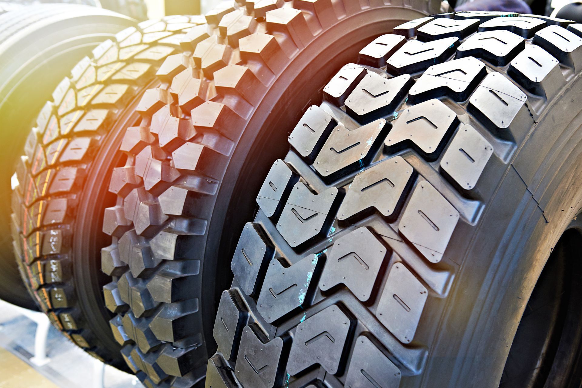 Close-up of black off-road tires with deep treads under warm sunlight