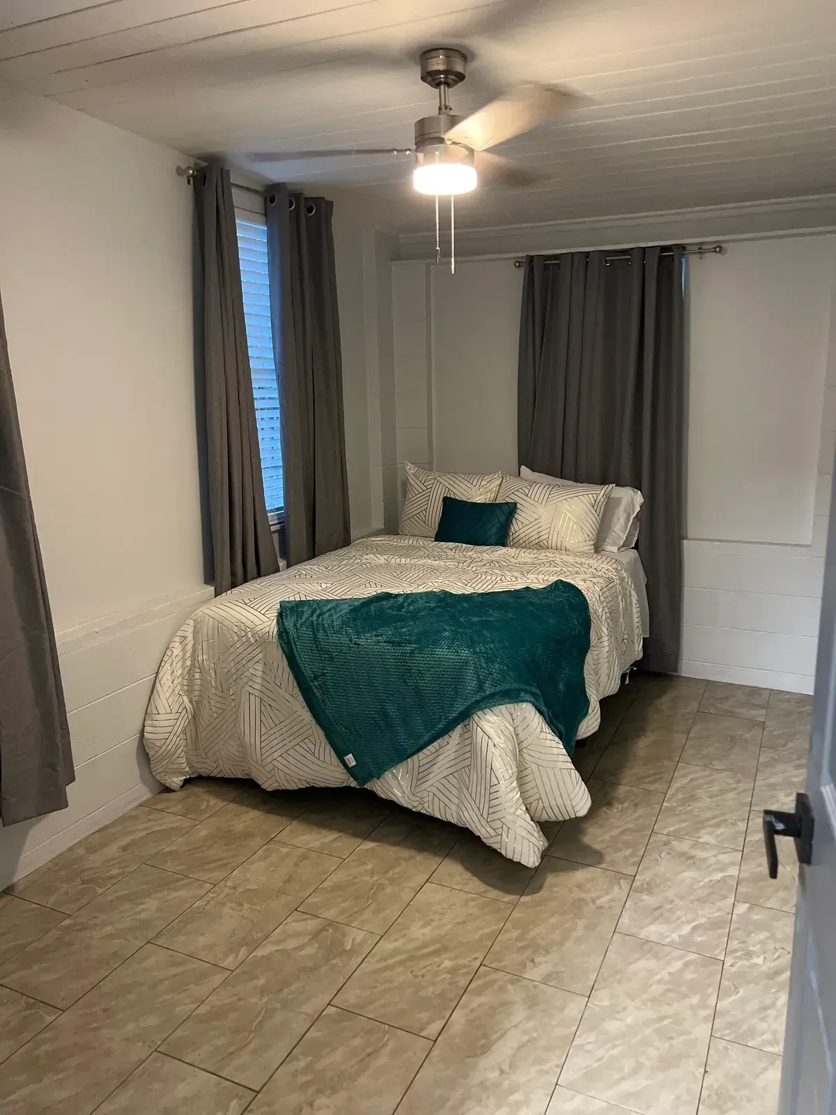 Modern building balcony overlooking the ocean with clear glass railing and greenery.