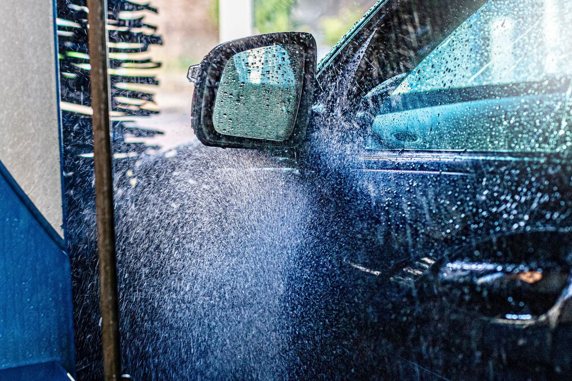 Black car being sprayed with water in a car wash.
