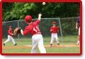 Boy in red uniform pitching a baseball, with teammates on a green field.