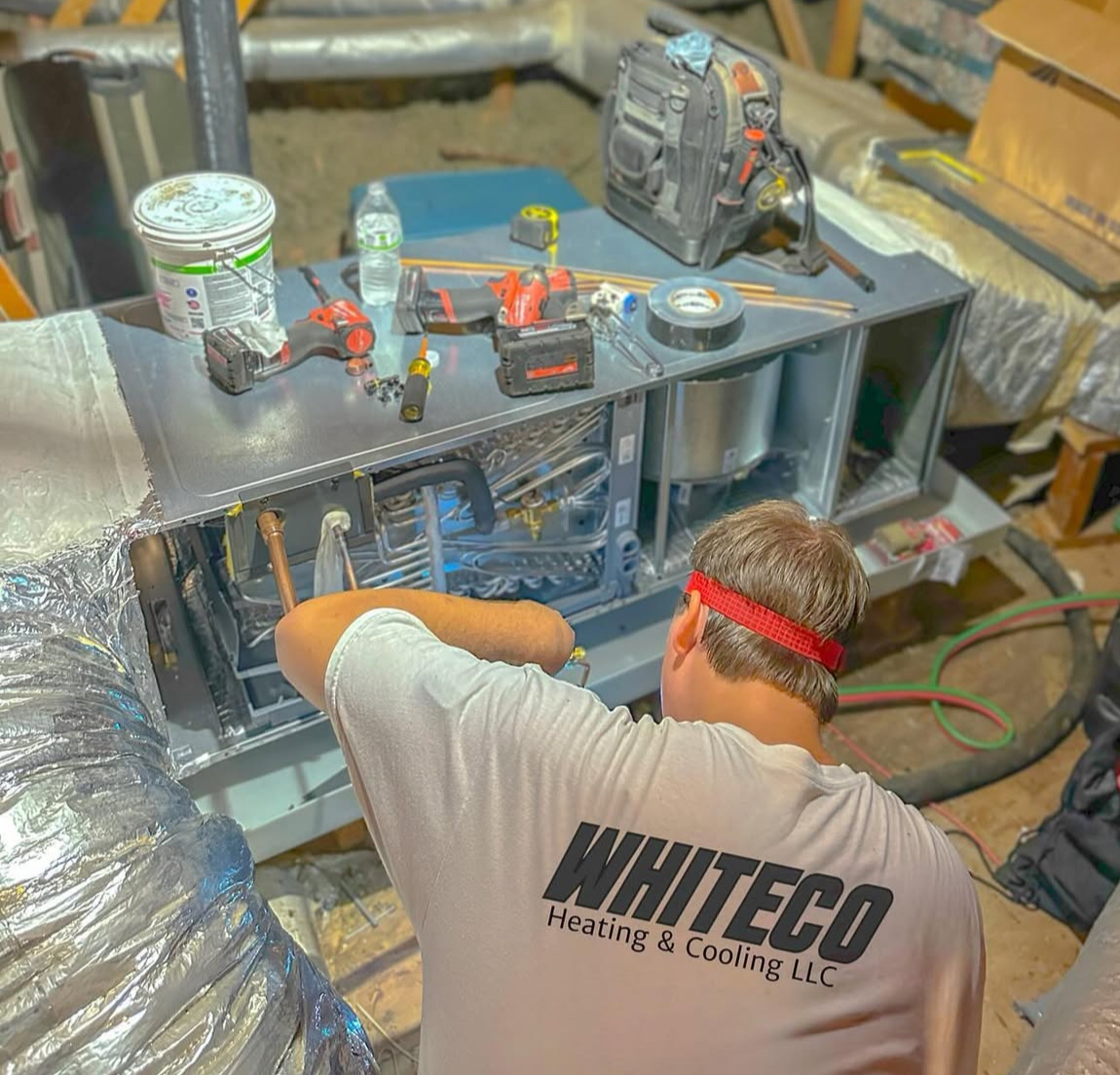 A man wearing a whiteco shirt is working on a machine.