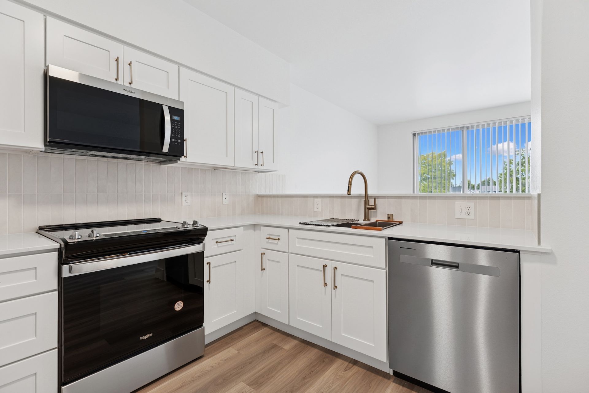 Modern kitchen with stainless steel appliances and white cabinets and countertops.