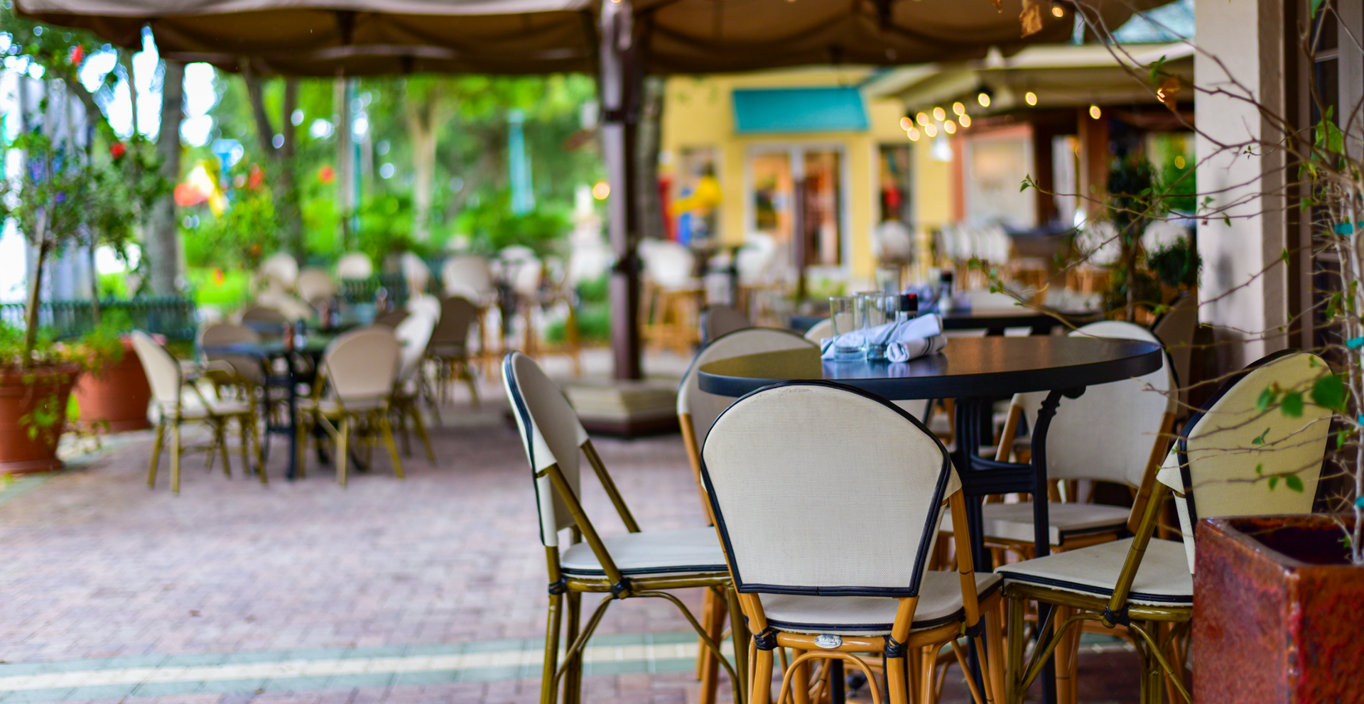 Tables and chairs outside of a restaurant with umbrellas