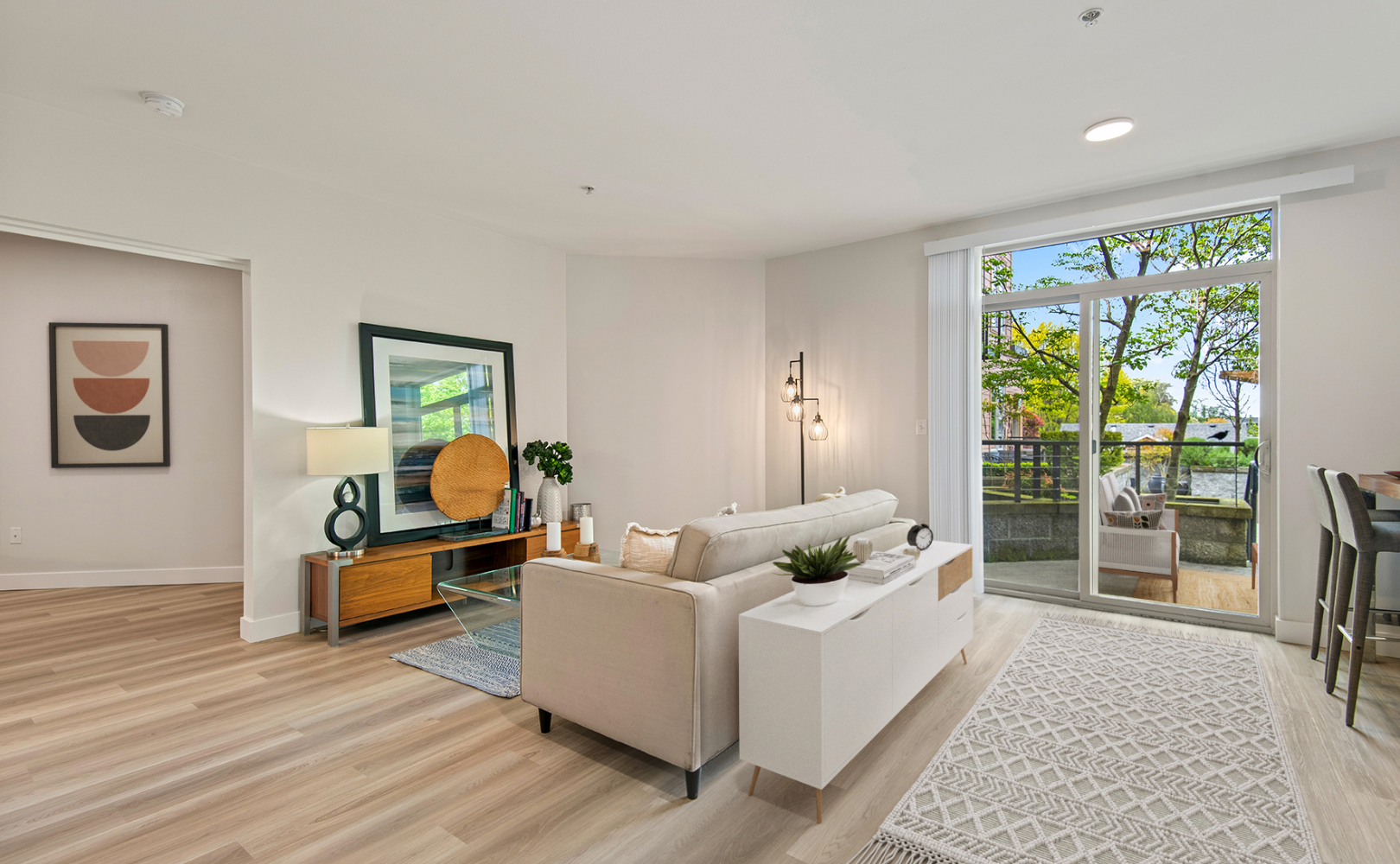 A living room with a couch , table and sliding glass doors leading to a balcony.