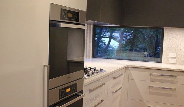 White Kitchen Cabinetry with Silver Accents — Builders  in Fernhill, NSW