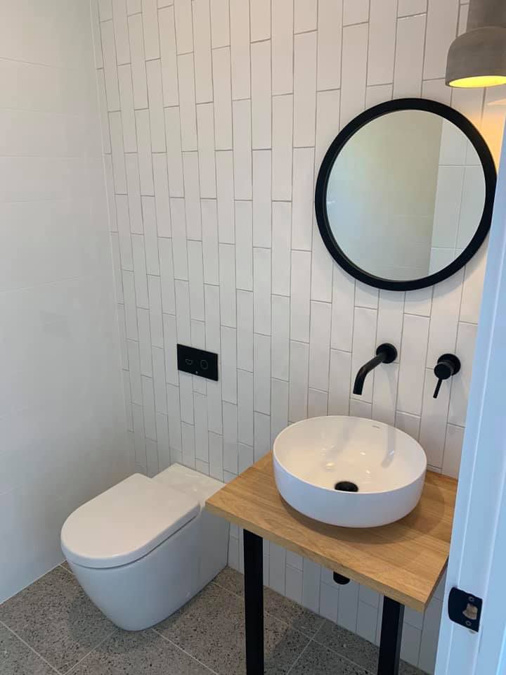 A Bathroom With a Toilet, Sink and Mirror — Craig Allman Construction Pty Ltd In Fernhill, NSW