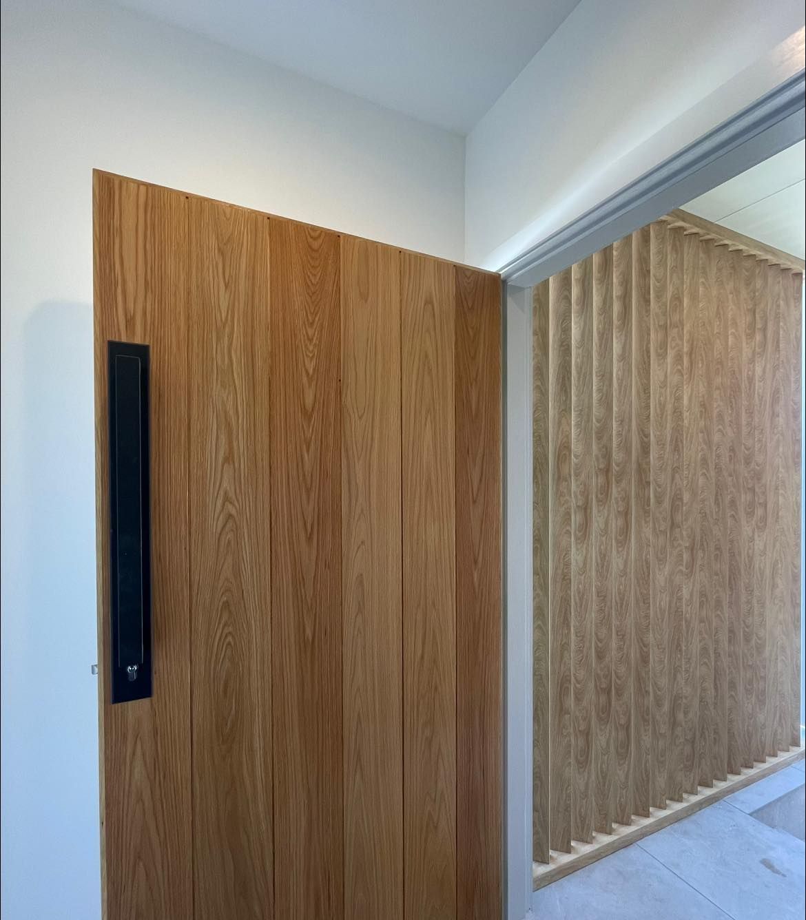 A Wooden Door With a Black Handle is in a Hallway — Craig Allman Construction Pty Ltd In Fernhill, NSW