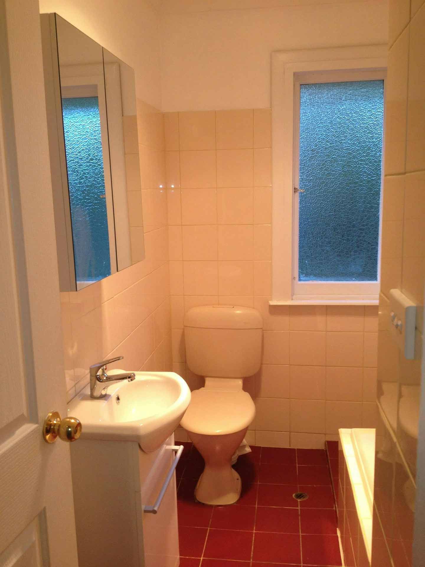 A Bathroom With a Toilet a Sink and a Window — Craig Allman Construction Pty Ltd In Thirroul, NSW