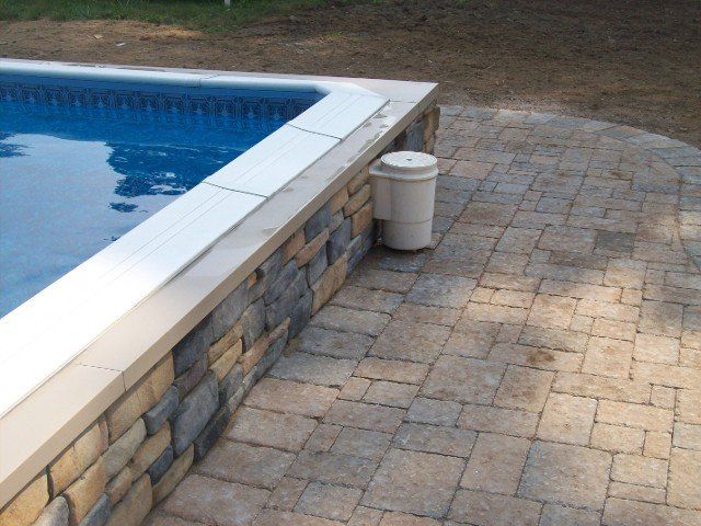 Back yard brick walkway with stone retainer wall for the pool - back yard landscaping services - Stellato Bros. Inc. in Feeding Hills, MA