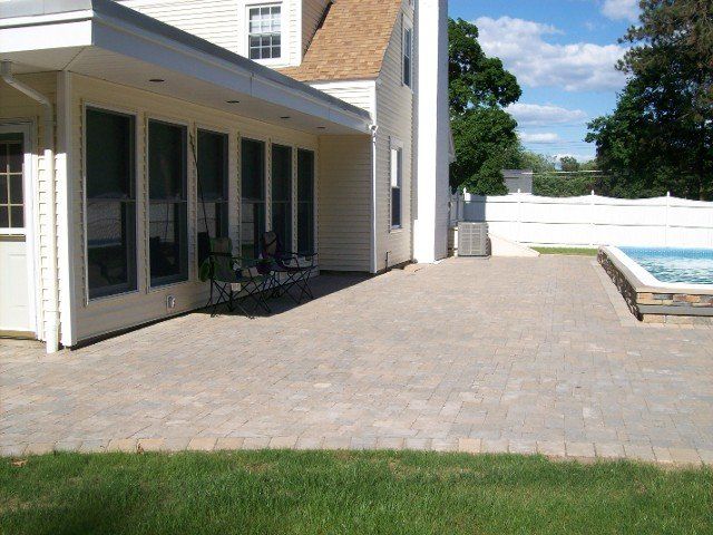 Back yard brick walkway with stone retainer wall for the pool - back yard landscaping services - Stellato Bros. Inc. in Feeding Hills, MA
