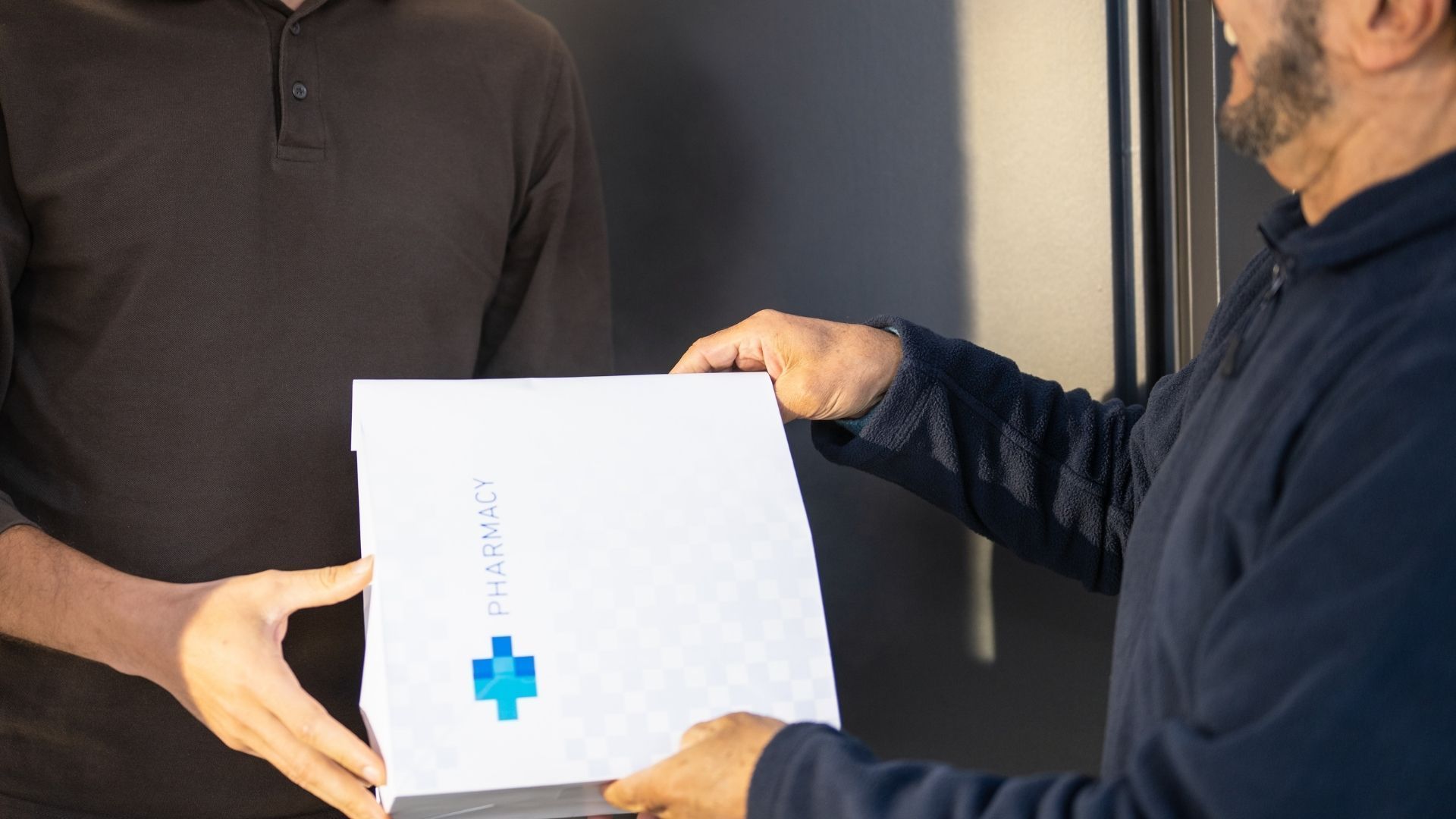 A man is handing a box to another man.