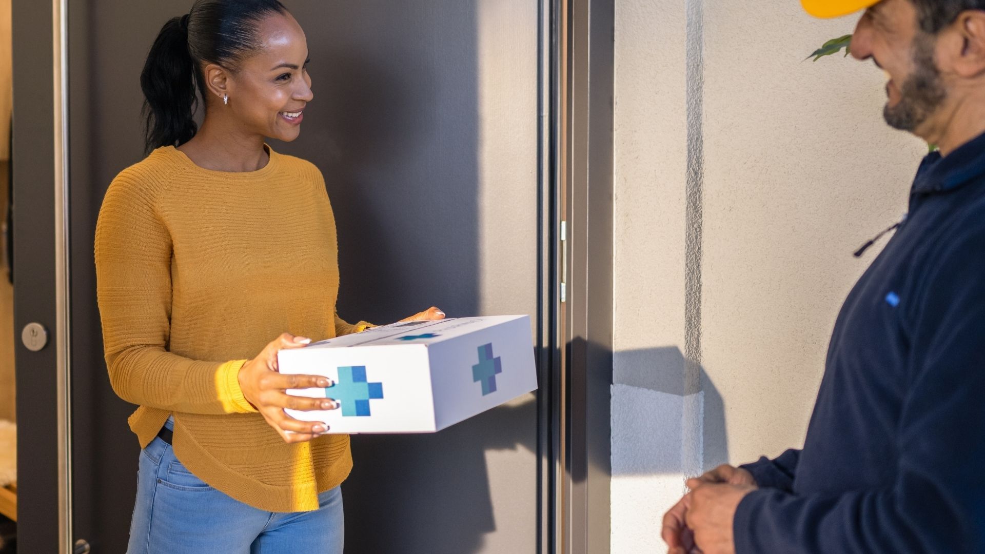 A woman is holding a box with a cross on it and giving it to a man.