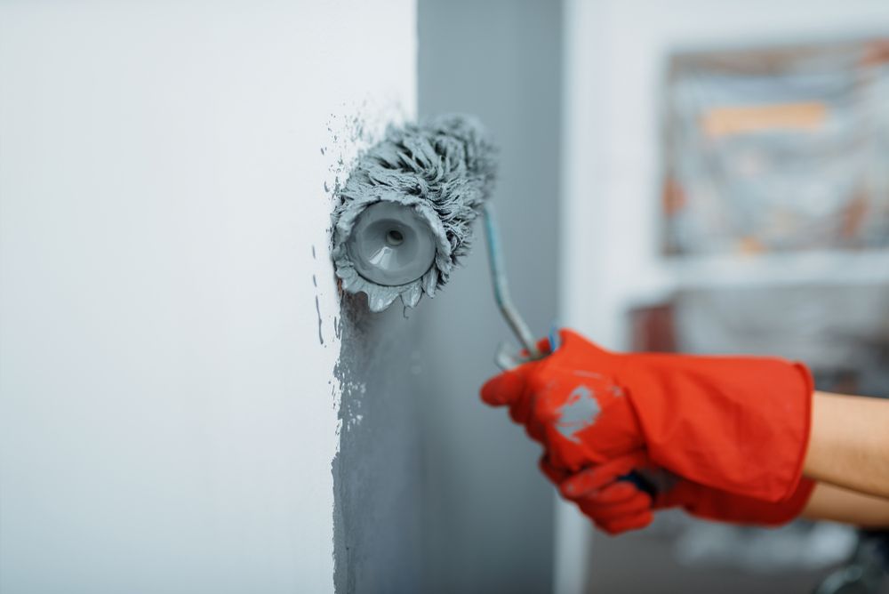 A person is painting a wall with a paint roller.