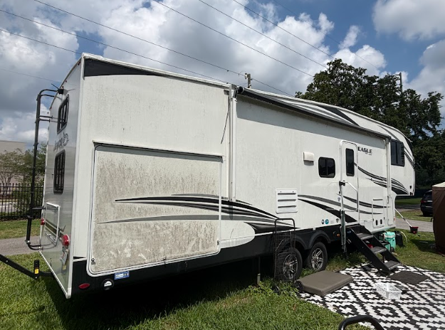 A white rv is parked in a grassy field.