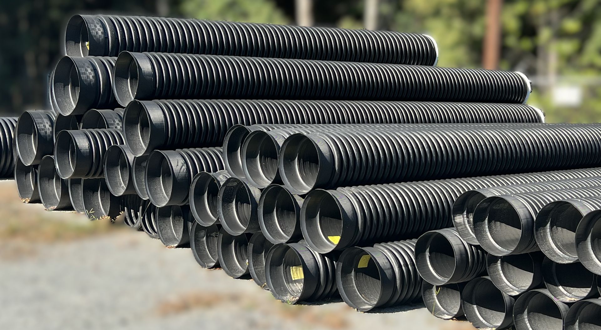 Pile of black corrugated plastic drainage pipes.