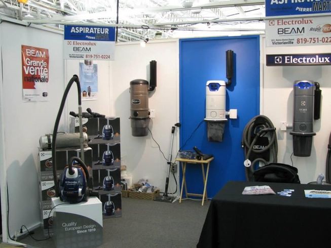 Stand d'exposition d'aspirateurs avec plusieurs modèles sur présentoirs dans un showroom intérieur
