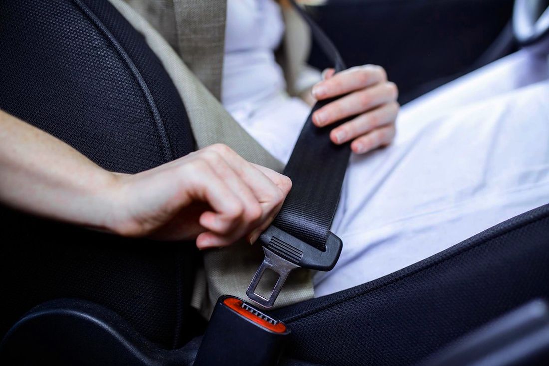Person buckling a seat belt in a vehicle.