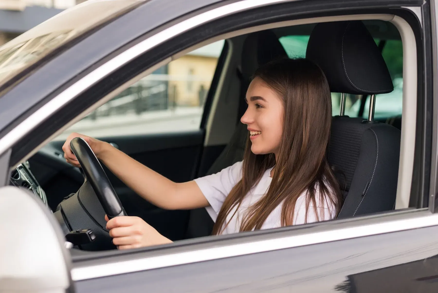 Young woman smiling while driving a car in Houston.