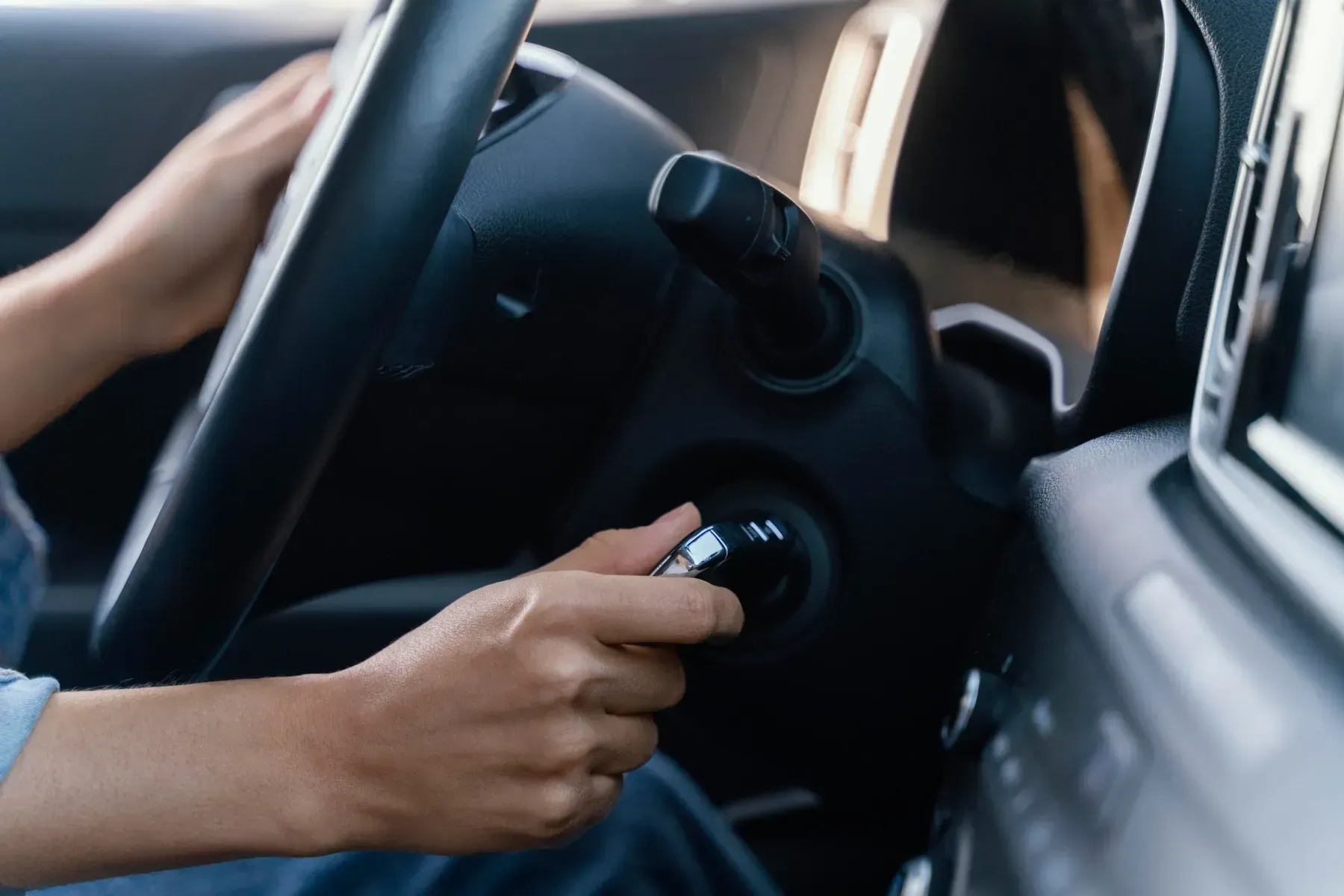 Person turning a car ignition key to start the vehicle.