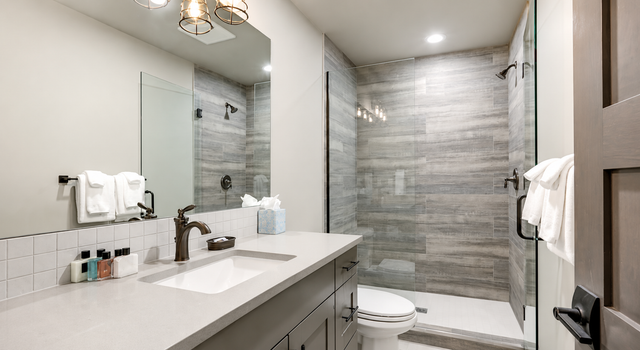 Modern bathroom with double vanity, large mirror, and gray tiled shower wall